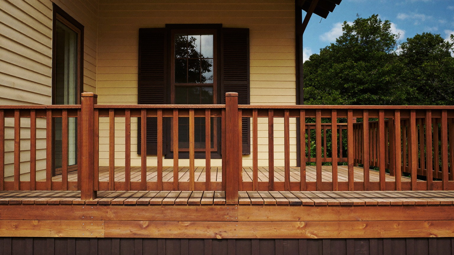 Editorial photograph of a rebuilt wooden deck on the back of an established Natick Massachusetts colonial: warm cedar-toned decking, natural wood