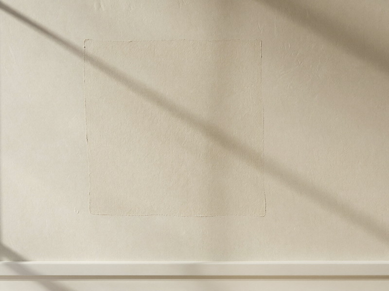 A freshly patched wall in an established home: a smooth rectangle of new joint compound feathered into the surrounding warm cream painted plaster wall,