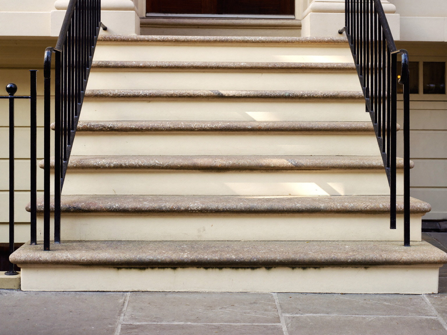 Repaired front entry steps of an established Natick colonial: fieldstone treads, crisp cream risers, a simple repainted black iron handrail, stone walk