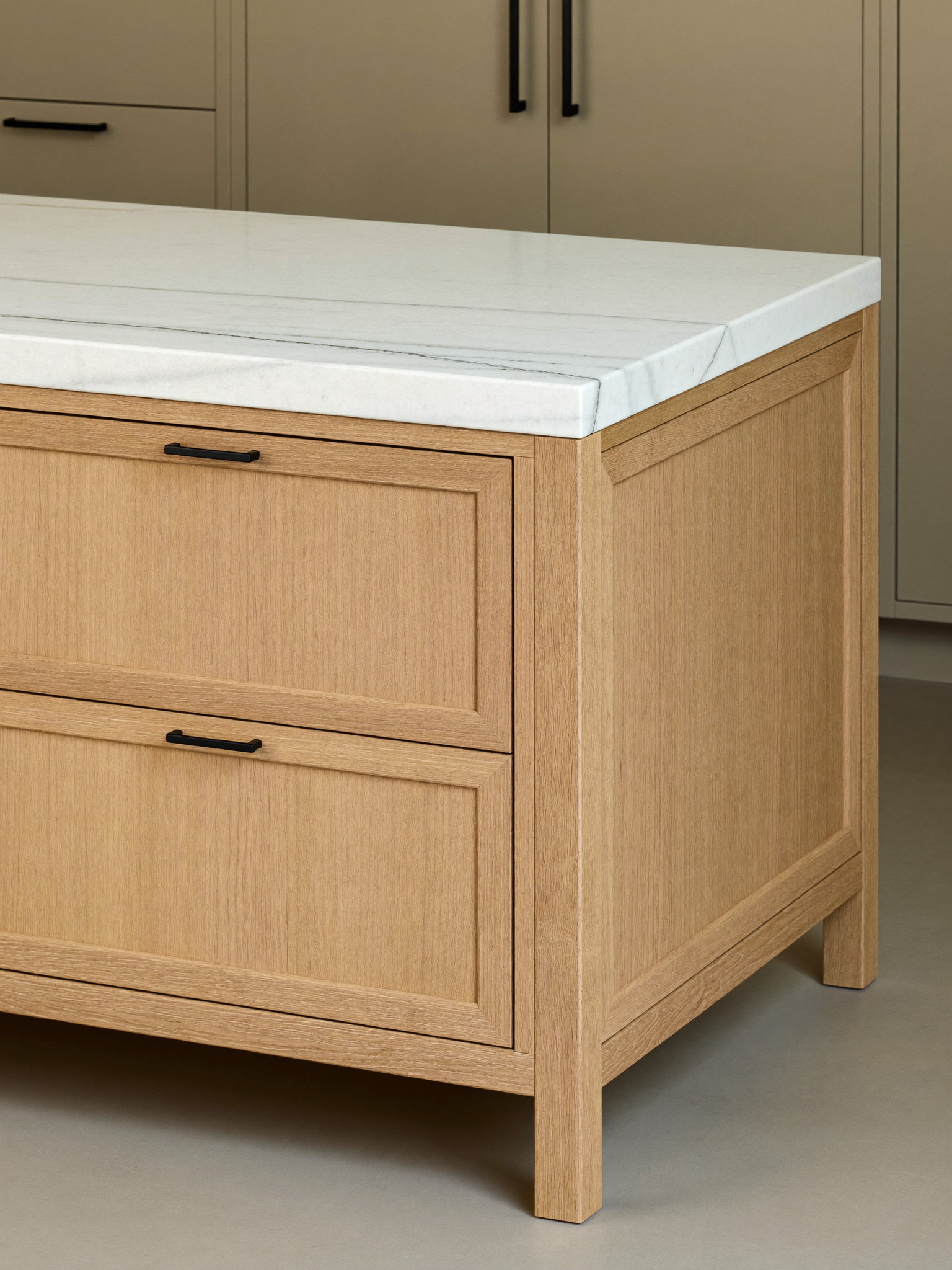 A generous white oak kitchen island with a honed white stone top and simple square legs, matte black hardware with smooth faces, warm greige inset