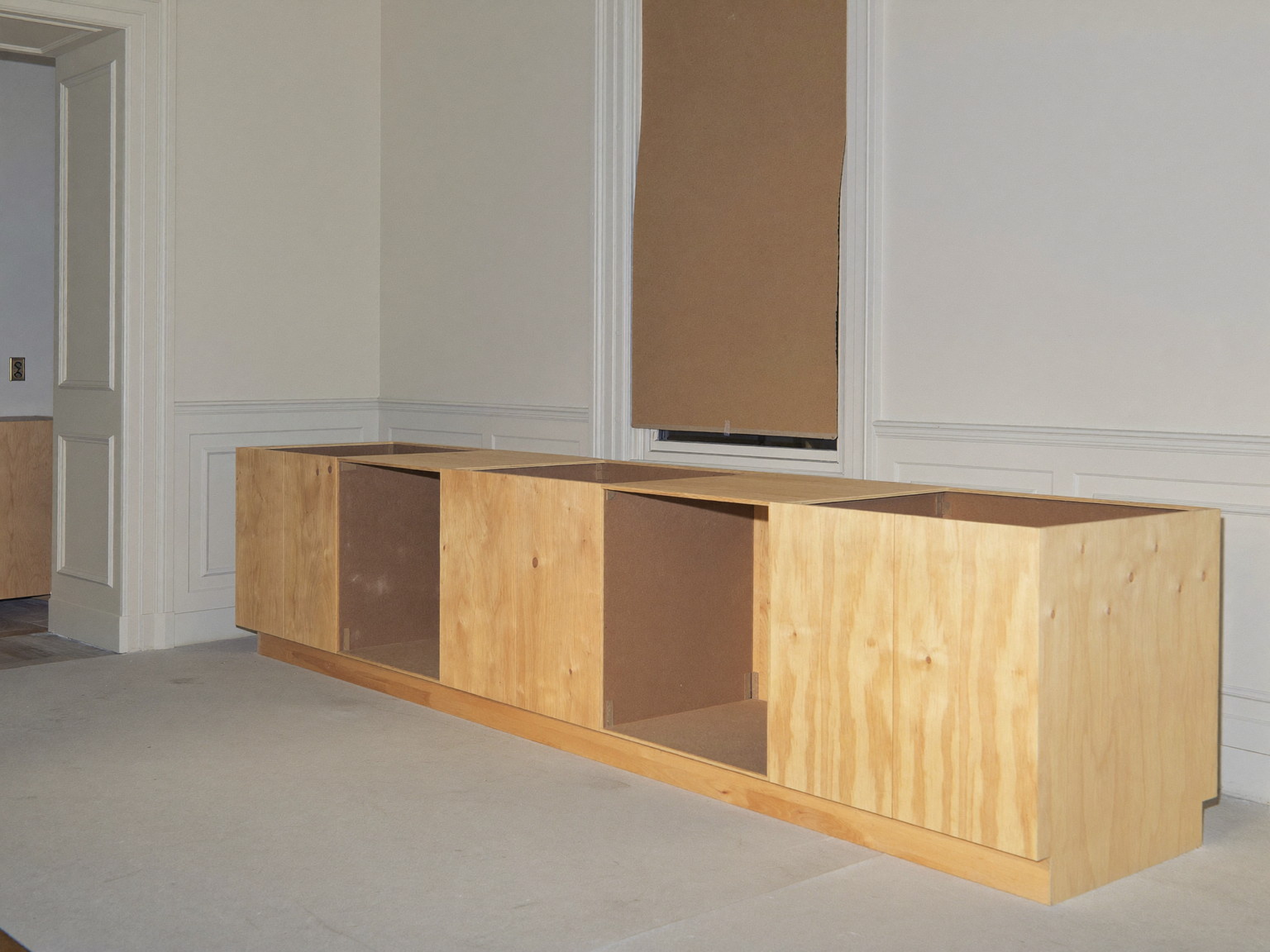 An empty quiet kitchen renovation in progress in an established colonial, completely unoccupied: unfinished inset cabinet frames standing fitted along one