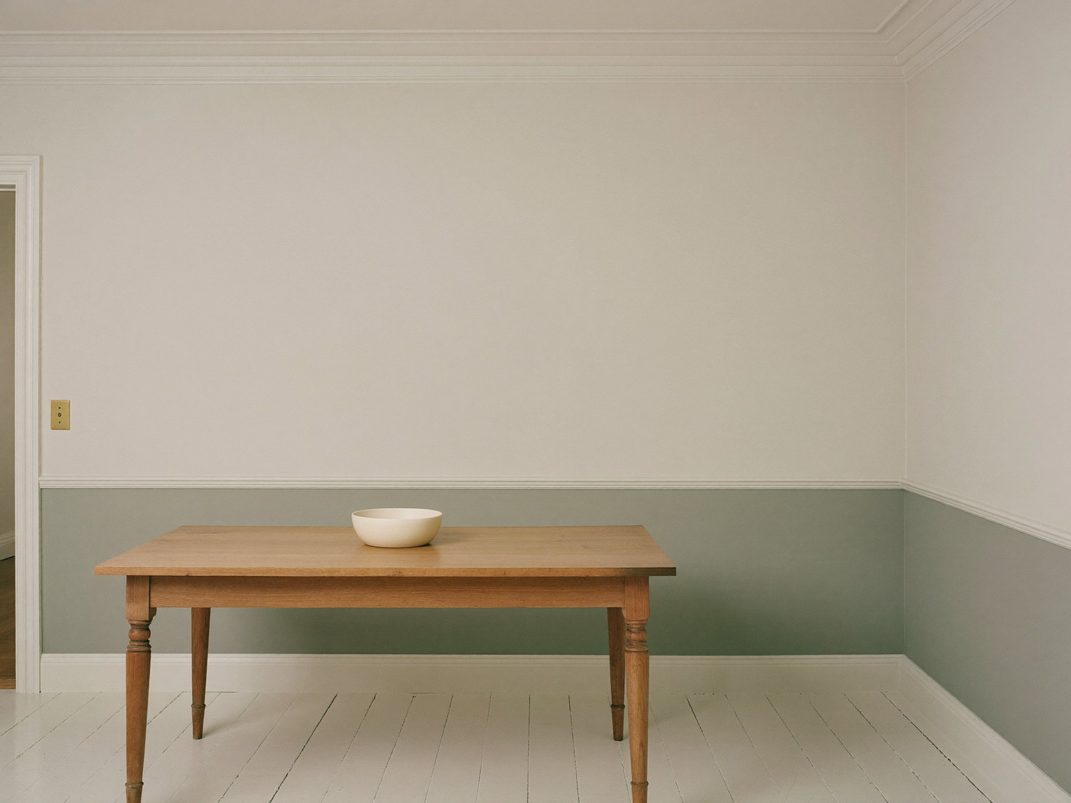 A repainted dining room in an established Needham colonial: soft warm white walls above a chair rail, deeper greige below, glossy white trim and crown