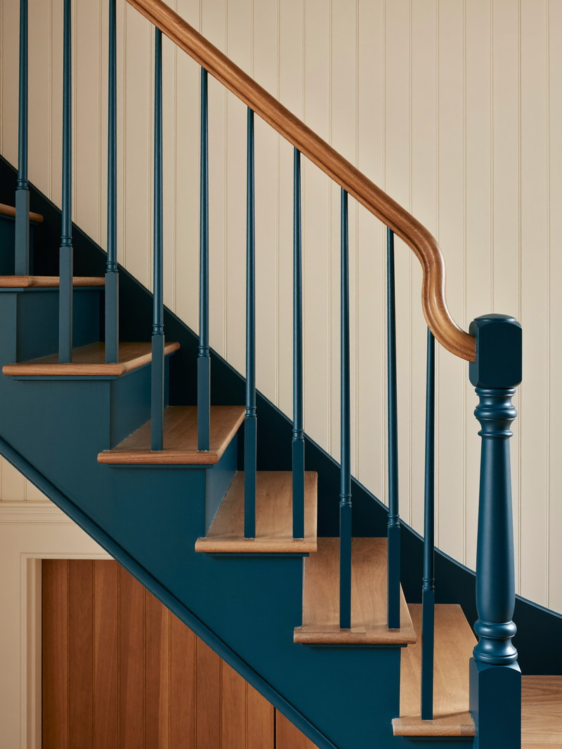 Oak stair treads with a teal-painted stringer and balusters leading down to the finished lower level