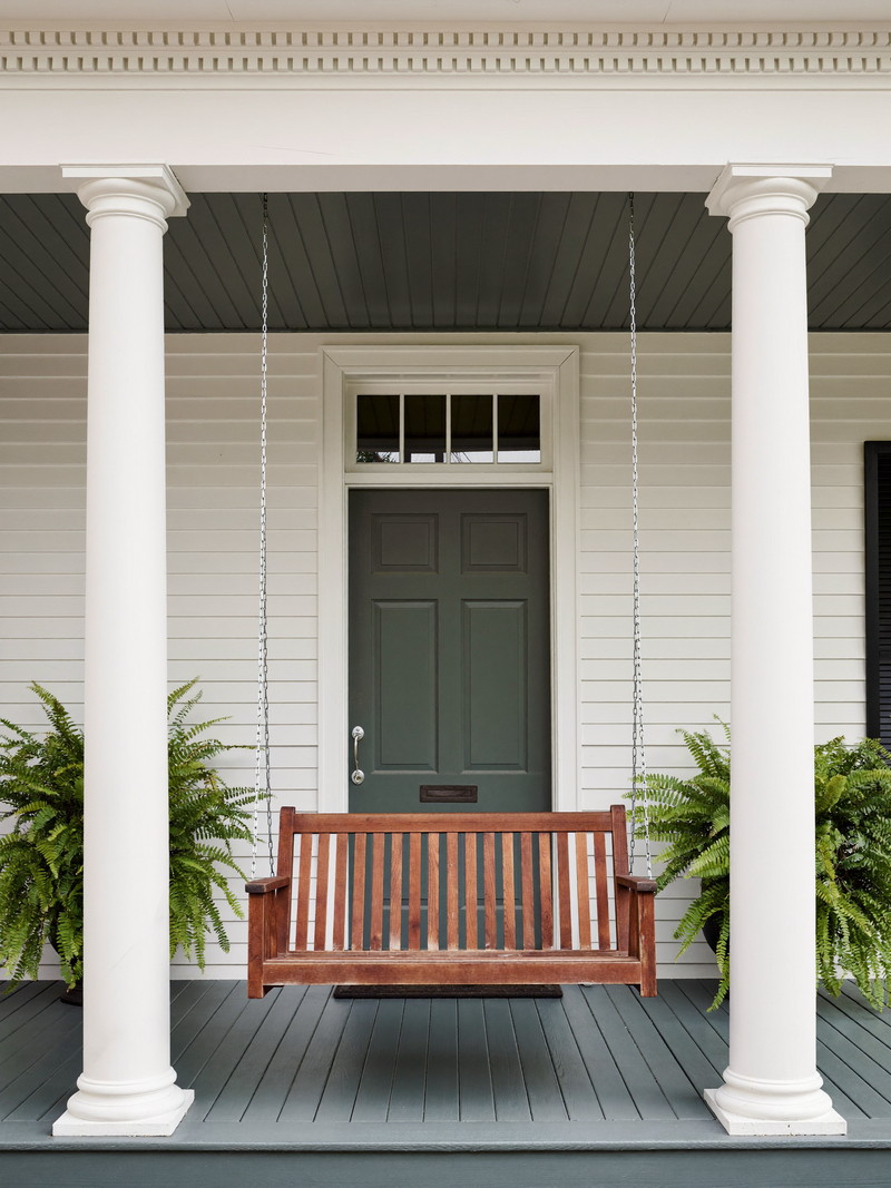 White farmer&rsquo;s porch with round columns, sky-blue beadboard ceiling, rocking chairs, and a stained wood floor