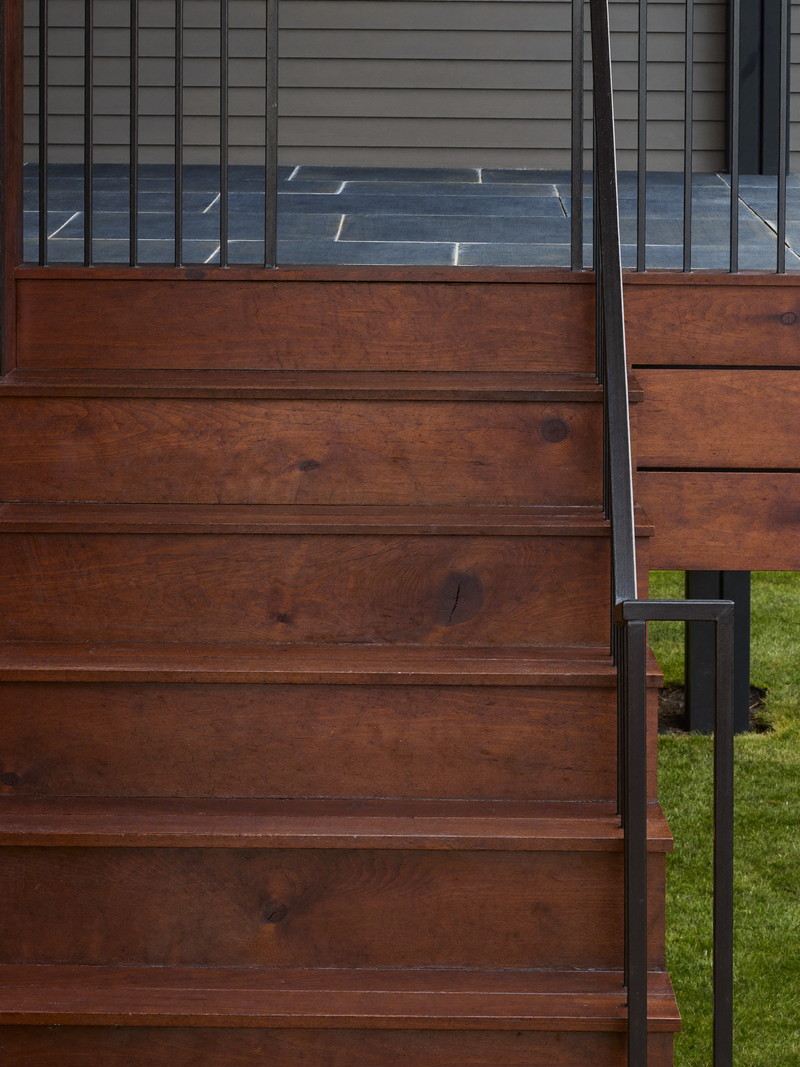 Deck stairs with slim black balusters and a chamfered cedar newel post