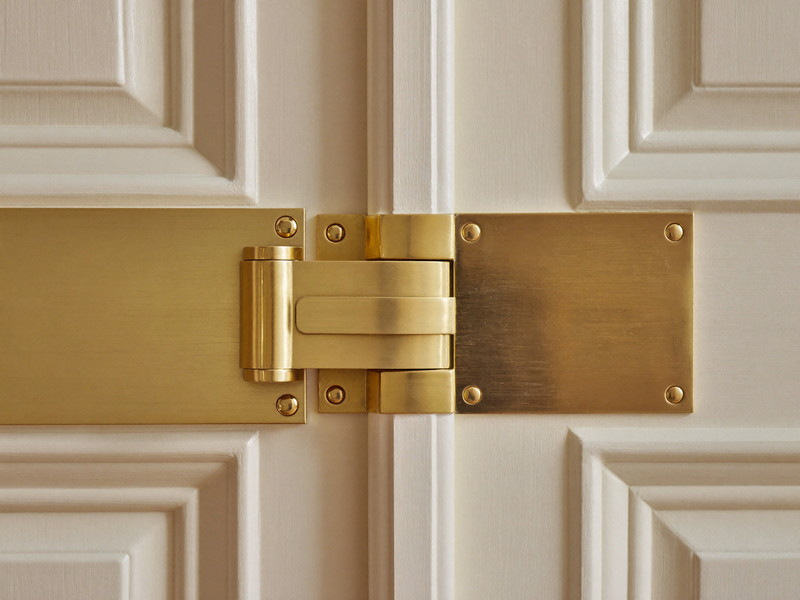 Solid brass surface-mounted latch fitted cleanly to a cream painted double door