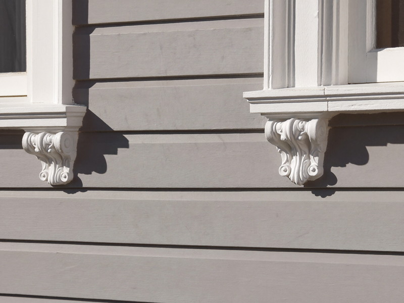 Sage clapboard siding meeting a bright white corner board and window casing