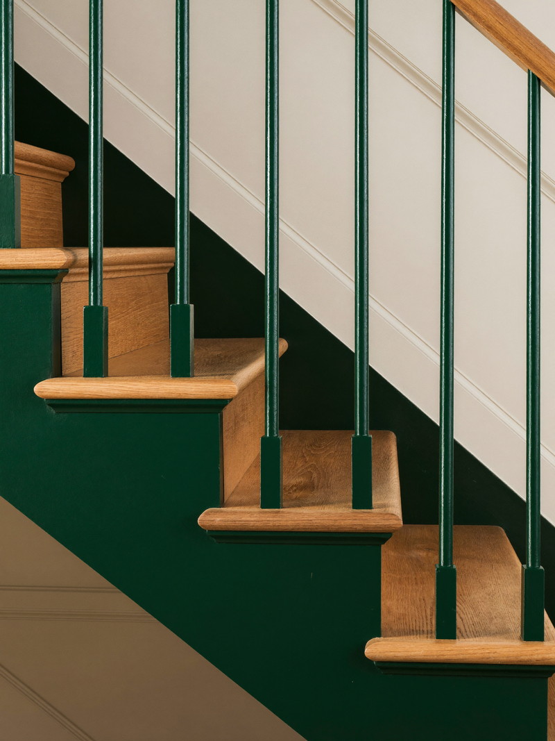 Oak stair treads with a teal-painted stringer and balusters leading down to the finished lower level
