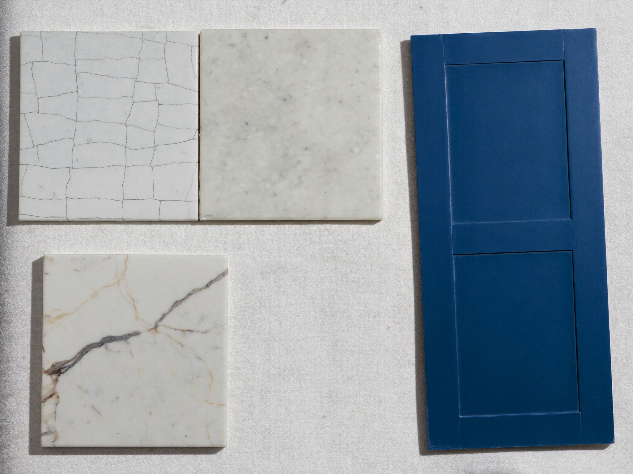 Bathroom material samples — sage handmade tile, carrara marble, walnut door sample, and brass hardware