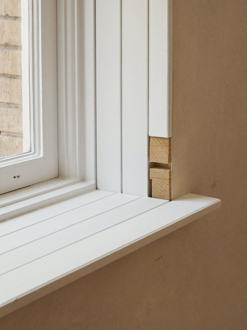 New primed window casing and stool fitted against an older plaster wall