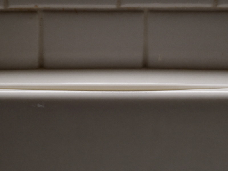 Smooth fresh caulk line where tile meets the tub edge — illustrative imagery