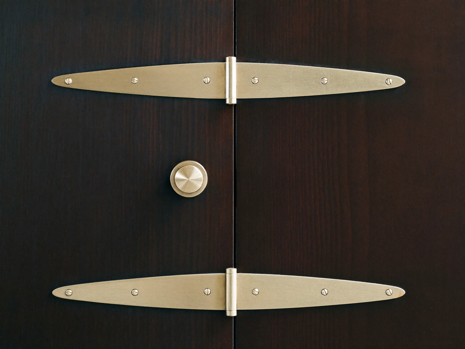 Brass hinges and quality door hardware laid out on dark stained wood