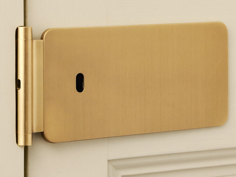 Solid brass surface-mounted latch fitted cleanly to a cream painted double door