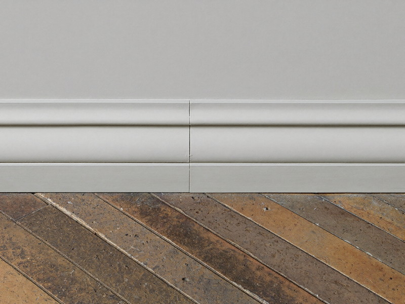 New baseboard and quarter-round scribed to an original oak floor — illustrative repair imagery