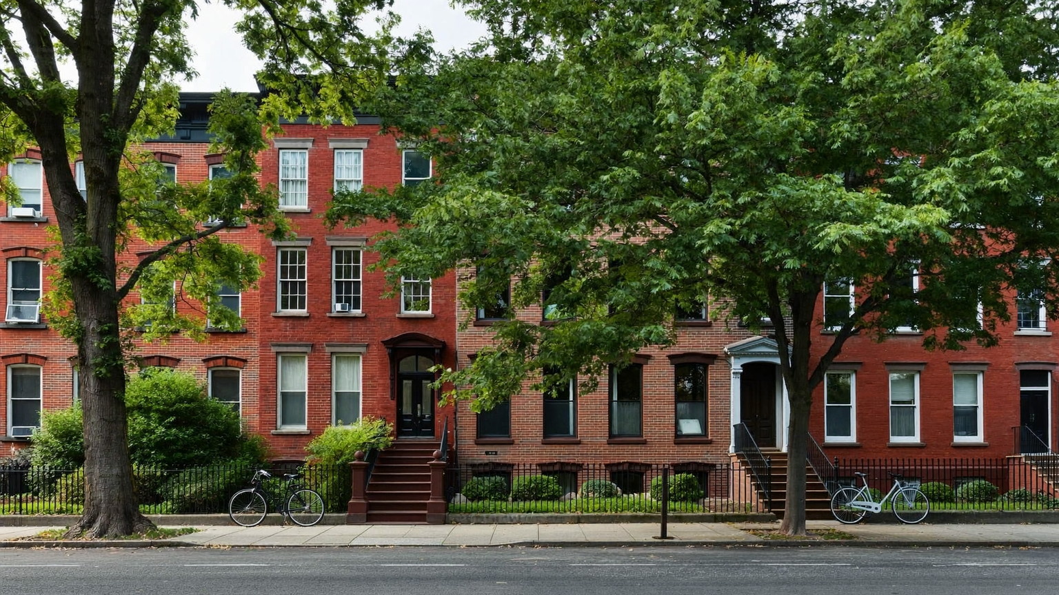 Quiet tree-lined South End street with brick rowhouses, brownstone stoops, and black iron fences