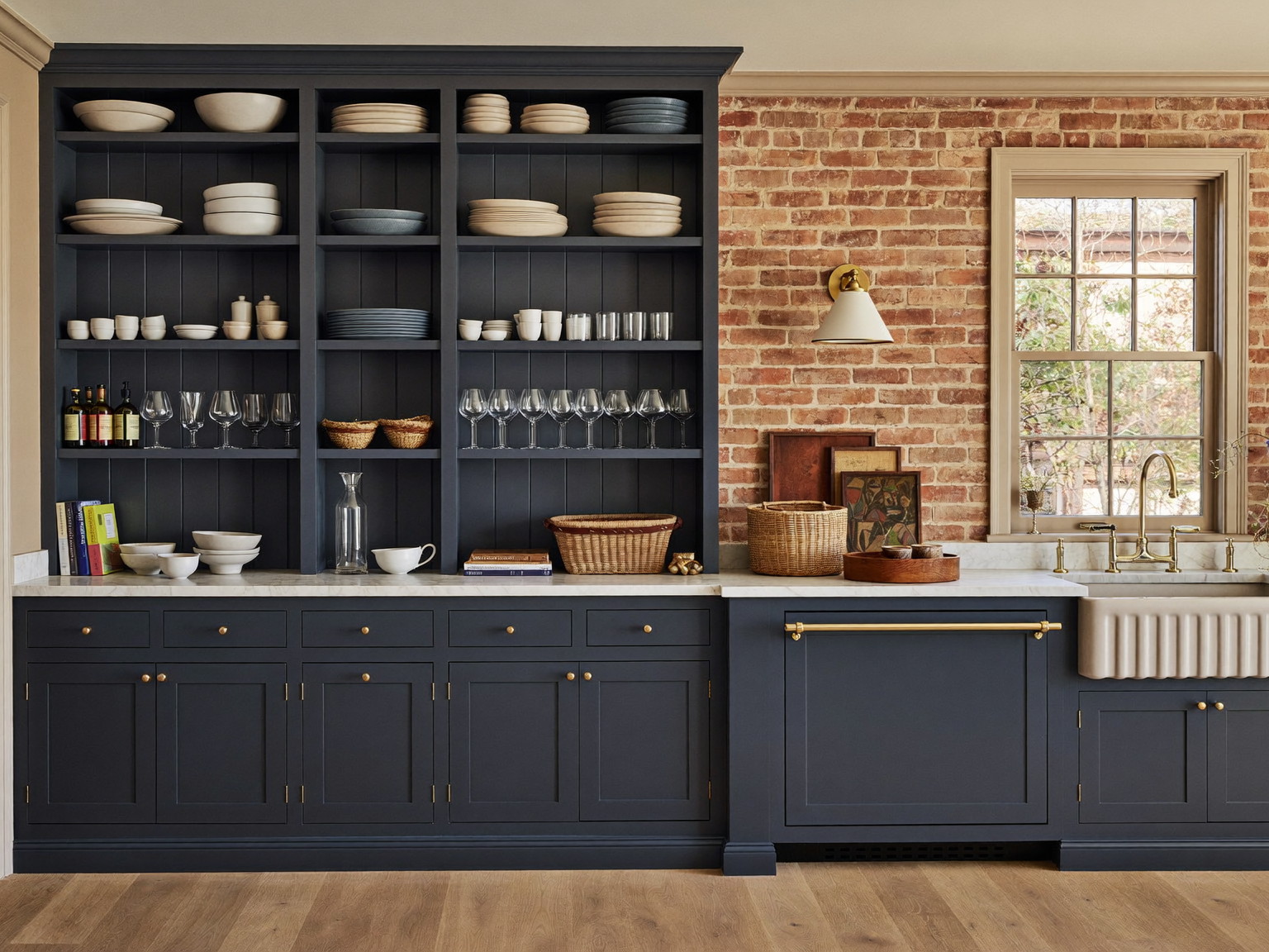 Completed narrow brownstone kitchen with navy cabinetry, marble counters, and exposed brick — illustrative imagery