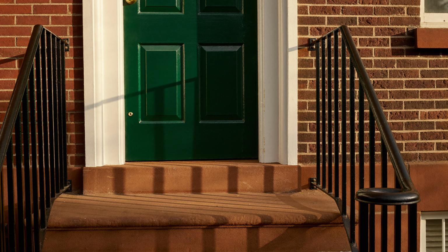 Freshly repainted sage-green Victorian entry with crisp white trim, columns, and porch detail