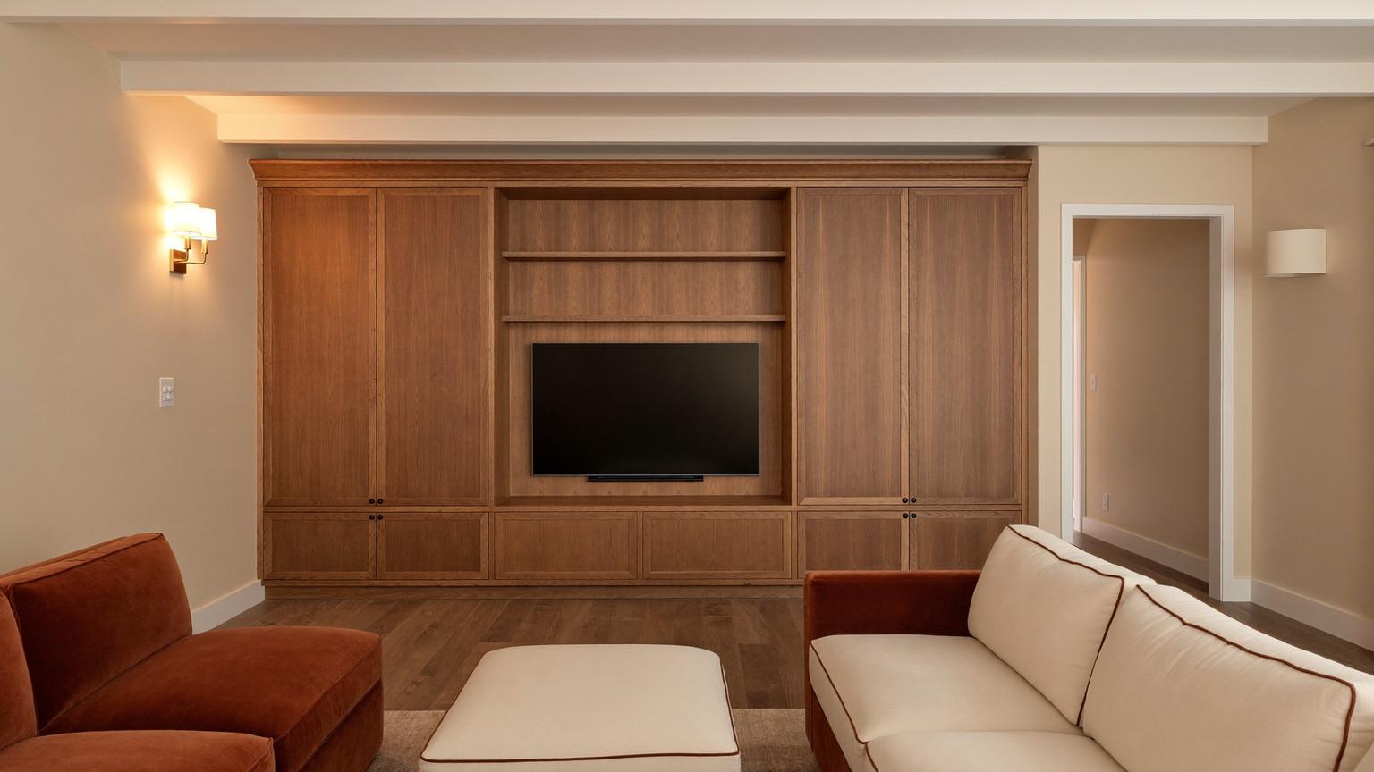 Editorial photograph of a finished lower-level family room beneath a classic Wellesley Massachusetts colonial: warm cream walls, white painted ceiling beams