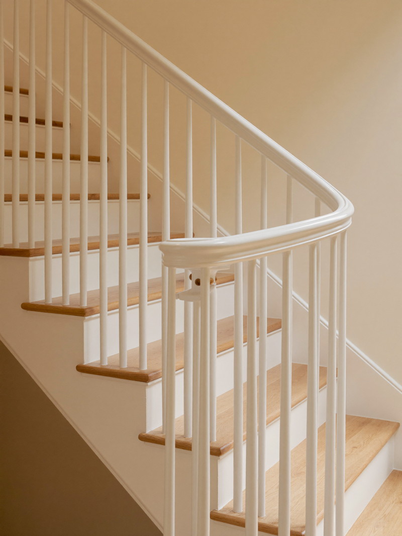 A refinished stair with crisp white risers and stringers, warm oak treads, and a curved white painted handrail, warm cream wall alongside, light from above
