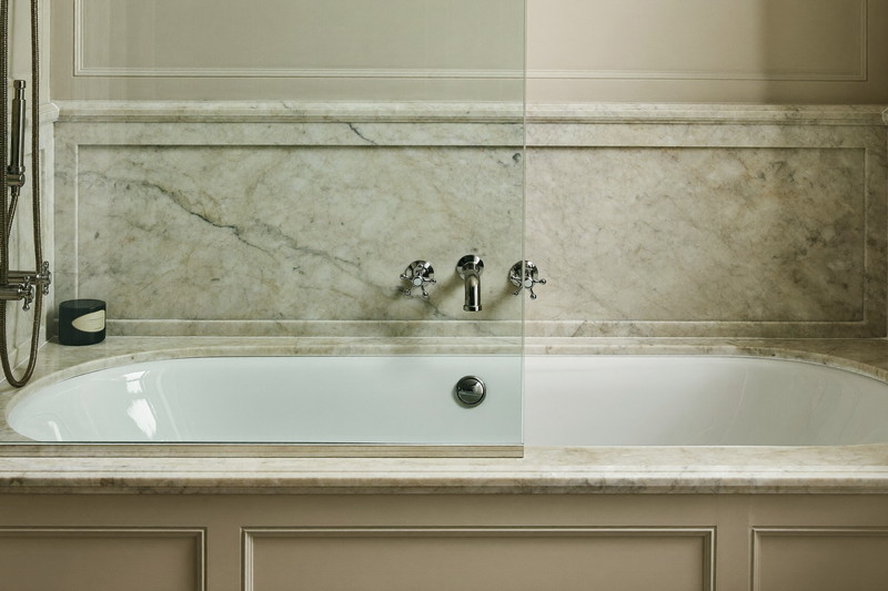 A refined tub and shower combination in a colonial bathroom: white tub, honed marble subway surround, polished nickel fixtures, clear glass screen, crisp and
