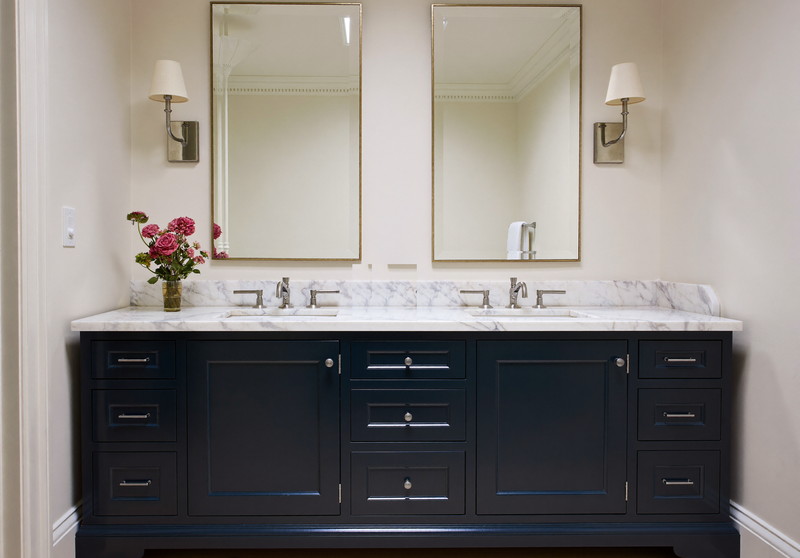A double navy vanity with honed white marble top and backsplash under two nickel-framed mirrors in a renovated colonial bathroom, polished nickel lever