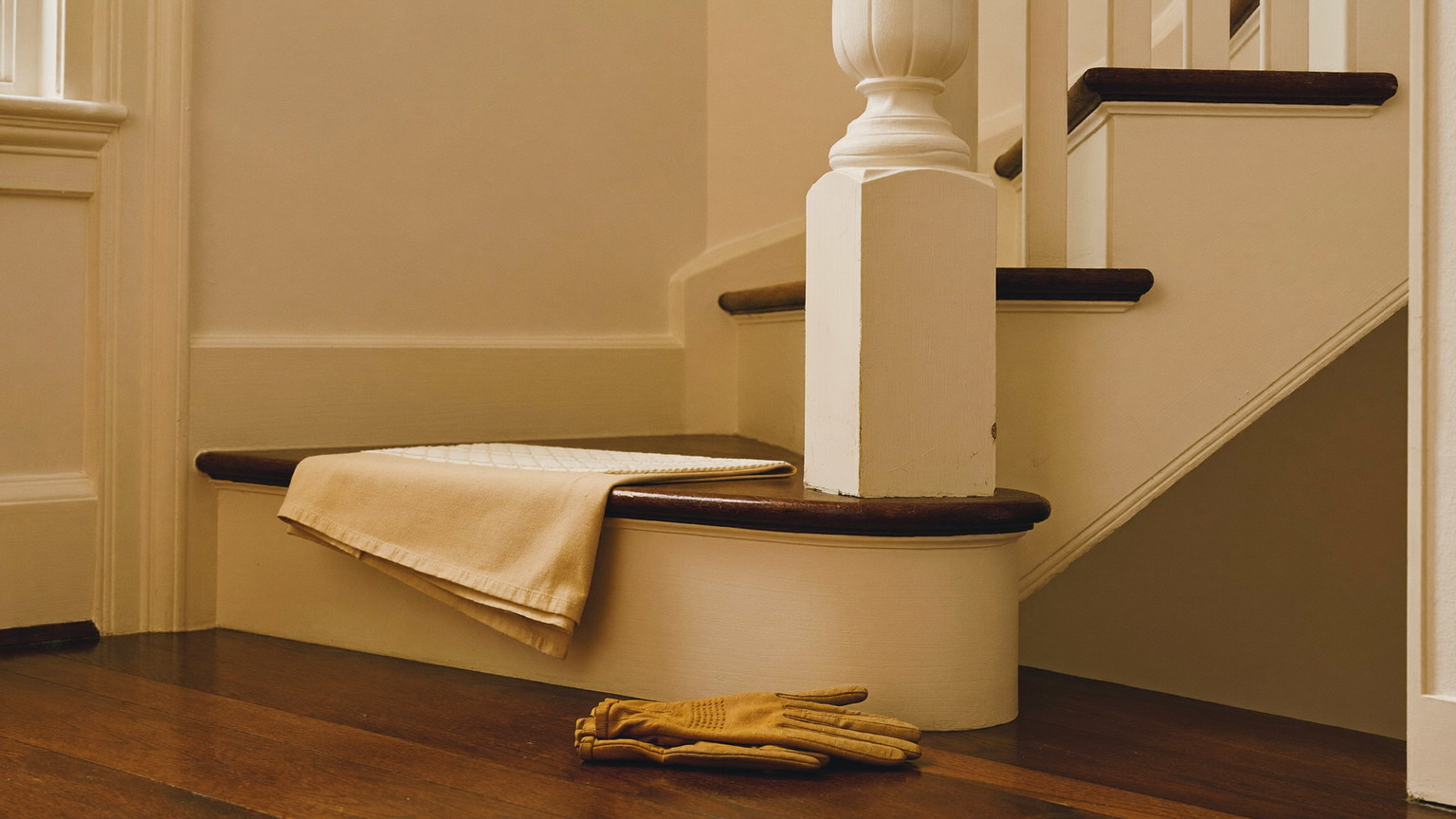 A quiet work moment in the front hall of a classic Wellesley Massachusetts colonial: a folded canvas drop cloth and plain tan leather work gloves resting on