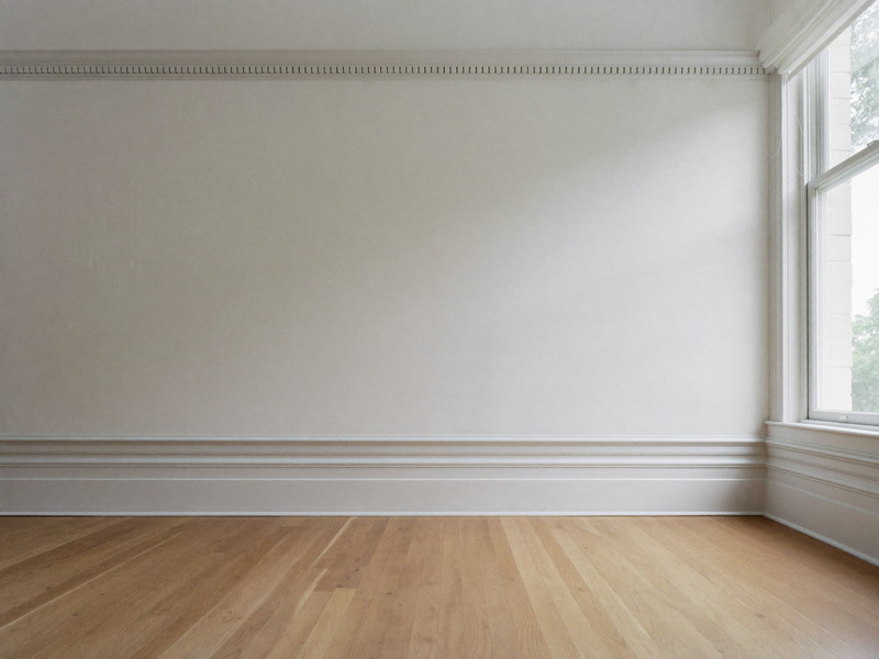 A restored corner of a classic colonial room: crisp white crown molding meeting a freshly painted warm white wall above refinished honey oak floor and bright